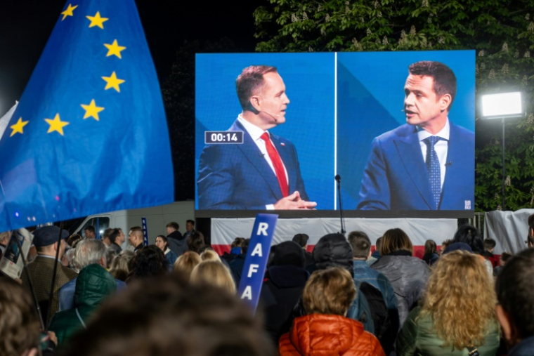 Des partisans du maire de Varsovie pro-européen, Rafal Trzaskowski (d), observent un débat entre leur candidat et son principal adversaire à la présidentielle, le nationaliste Karol Nawrocki (g), à Varsovie, le 12 mai 2025 ( AFP / Wojtek RADWANSKI )
