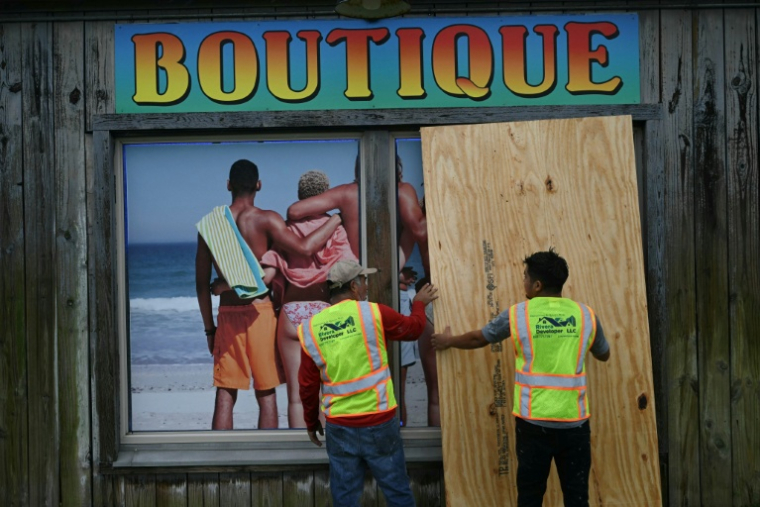 Des ouvriers barricadent la devanture d'un magasin à Pensacola Beach, avant l'arrivée de l'ouragan Isaias, le 9 octobre 2026 en Floride ( AFP / RONALDO SCHEMIDT )