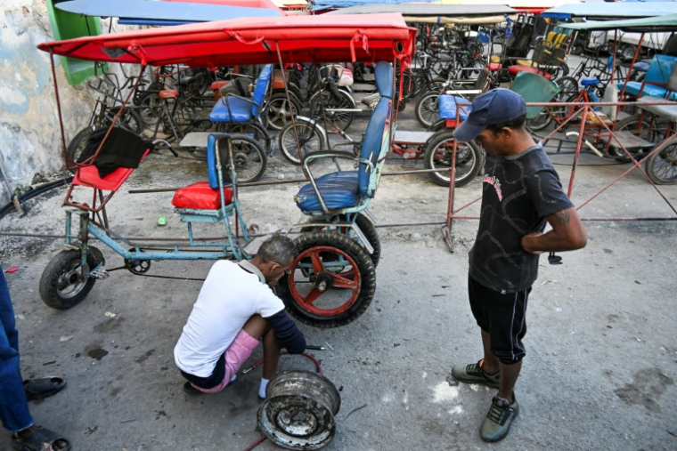 Un mécanicien répare le pneu d'un taxi-bicyclette à La Havane, Cuba, le 13 février 2026 ( AFP / YAMIL LAGE )