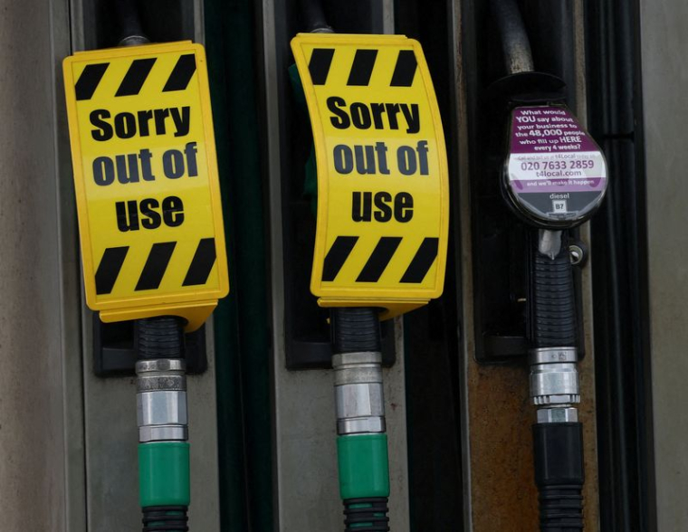 Des panneaux indiquant que les pompes à essence sans plomb sont hors d'usage sont suspendus aux becs des pompes vides sur le parvis d'une station-service à Manchester