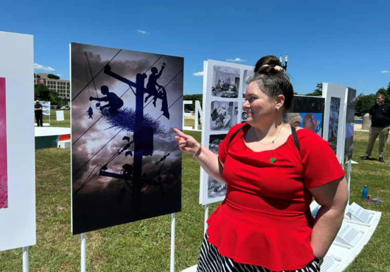 Kylie Nidever, Texane de 36 ans, dont le quartier a été ravagé par les inondations catastrophiques de début juillet 2025, pointant une oeuvre d'art inspirée par cette tragédie, à Washington, le 24 juin 2026 ( AFP / Charlotte CAUSIT )