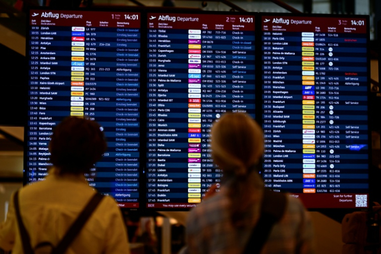 Des passagers regardent des panneaux d'affichage à l'aéroport Berlin-Brandebourg, le 20 septembre 2025 à Schoenefeld, au sud-est de la capitale allemande ( AFP / Tobias SCHWARZ )