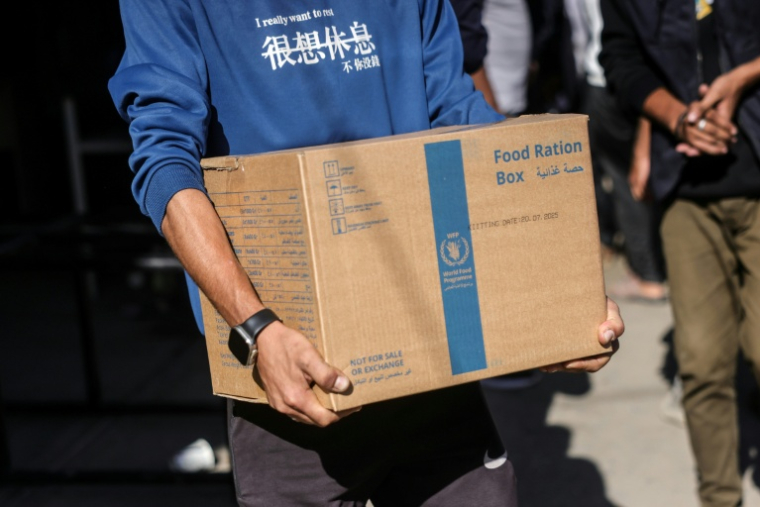 Un Palestinien transporte une boîte de rations alimentaires fournie par le Programme alimentaire mondial (PAM) à Al-Zawayda, au centre de la bande de Gaza, le 27 octobre 2025 ( AFP / BASHAR TALEB )