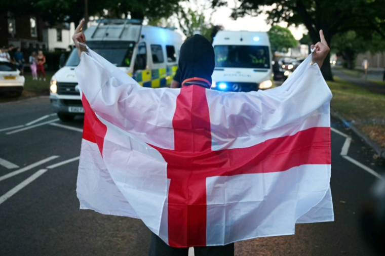 Un manifestant enveloppé dans le drapeau anglais lors d'un rassemblement anti-migrants à Epping, au nord-est de Londres, le 20 juillet 2025 ( AFP / JUSTIN TALLIS )