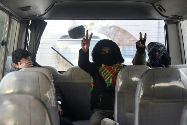 Des jeunes hommes masqués quittent Souleimanieh, au  Kurdistan irakien, pour rejoindre Hassaké, dans une région kurde du nord-est de la Syrie, le 20 janvier 2026 ( AFP / Shwan MOHAMMED )