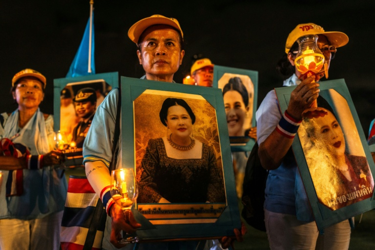 Des partisans de la famille royale tiennent des portraits de la reine mère Sirikit, décédée vendredi, ici le 12 août 2025 à Bangkok ( AFP / Chanakarn Laosarakham )