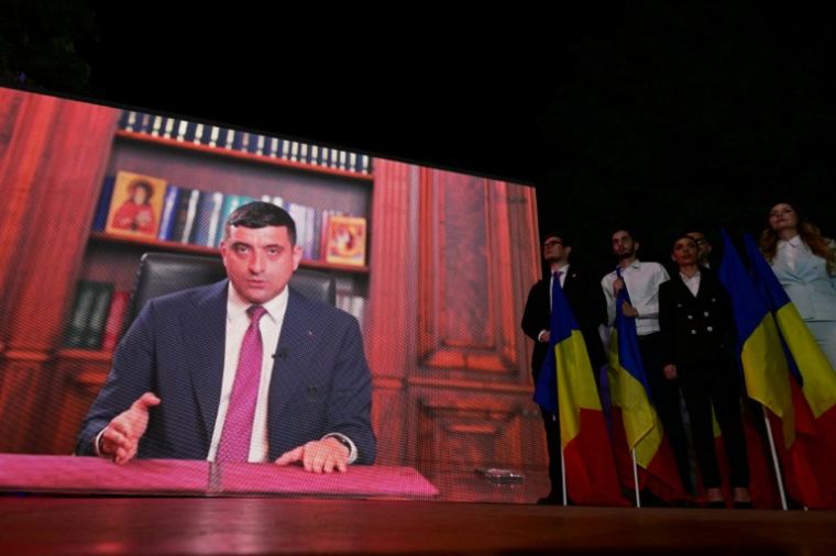 Ecran géant diffusant un message vidéo du candidat d'extrême droite George Simion, le 4 mai 2025 à Bucarest ( AFP / Daniel MIHAILESCU )
