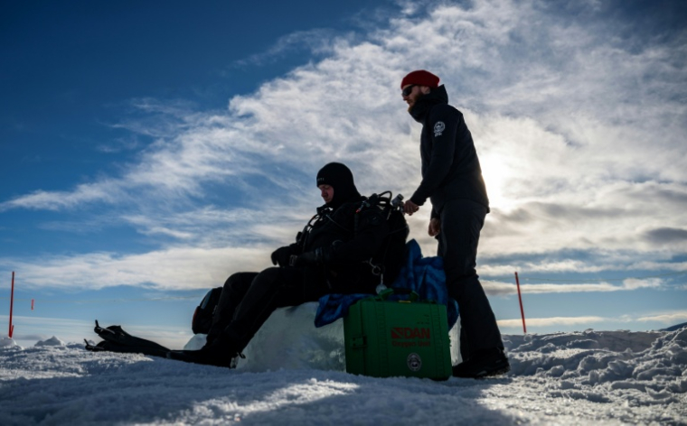 Erik Wurz, plongeur-chercheur, Erik Wurz (D), derrière un plongeur lors d'un stage scientifique de plongée polaire, le 14 mars 2026 sur le lac de Kilpisjärvi, à l'extrême nord-ouest de la Finlande ( AFP / John MACDOUGALL )
