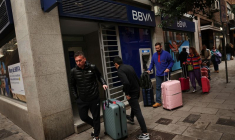 Des personnes portant des valises passent devant une agence de la banque BBVA à Madrid.