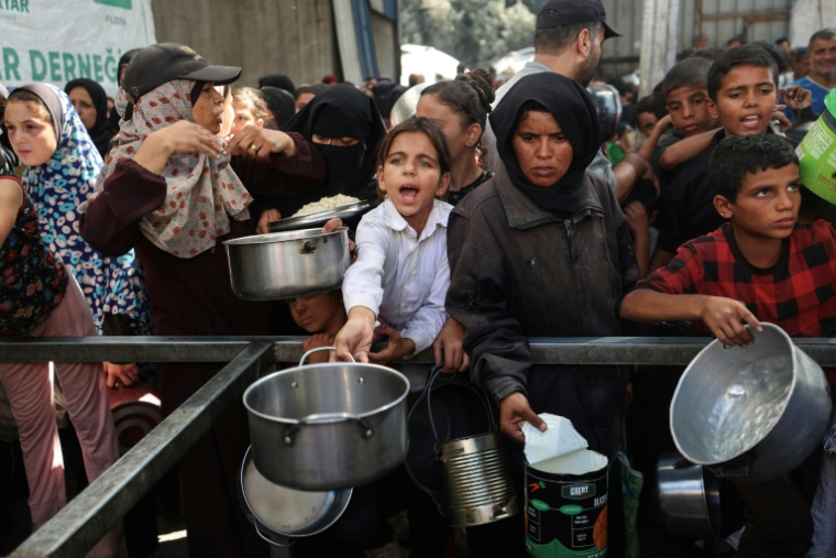 Des Palestiniens se rassemblent pour recevoir des portions alimentaires distribuées par une cuisine caritative dans le camp de réfugiés de Nousseirat, dans le centre de la bande de Gaza, le 15 octobre 2025 ( AFP / Eyad BABA )