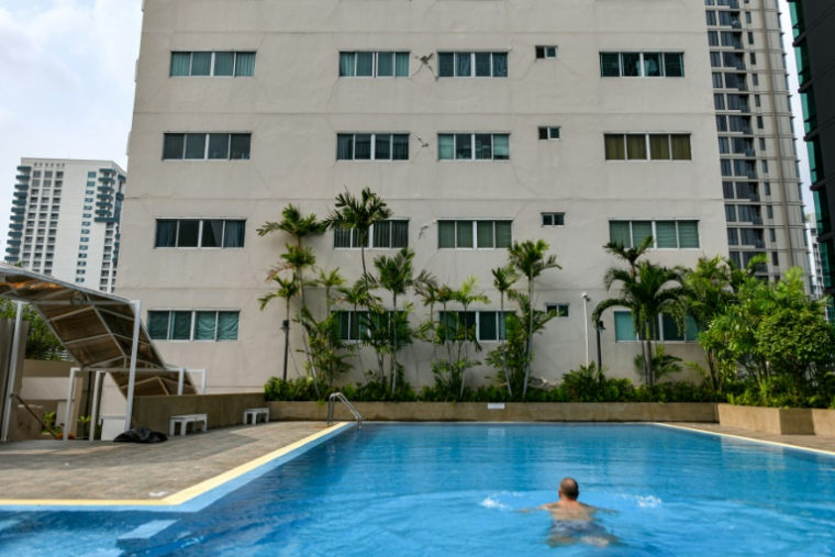 Un homme nageant dans une piscine d'un immeuble résidentiel de Bangkok le 30 mars 2025, dont le mur a été fissuré par le séisme qui a frappé la Birmanie et la Thaïlande deux jours plus tôt ( AFP / Amaury PAUL )