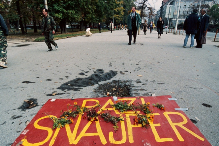 "Attention aux snipers", est-il inscrit sur une banderole posée au sol de cette rue de Sarajevo à côté du cratère causé par l'explosion d'une grenade, le 1er novembre 1995, en hommages victimes de la guerre de Bosnie ( AFP / Odd ANDERSEN )