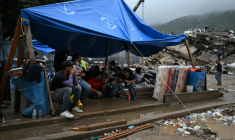 Des rescapés du double séisme s’abritent sous une bâche tandis que les secouristes fouillent les décombres des immeubles effondrés à Caraballeda, dans l’État de La Guaira, au Venezuela, le 11 juillet 2026 ( AFP / Raul ARBOLEDA )