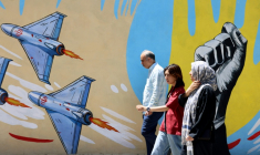 Des Iraniens passent devant des graffitis anti-américains et anti-israéliens, à Téhéran le 10 mai 2026 ( AFP / ATTA KENARE )