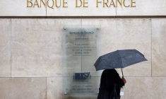 Une femme tenant un parapluie passe devant le bâtiment de la Banque de France à Paris