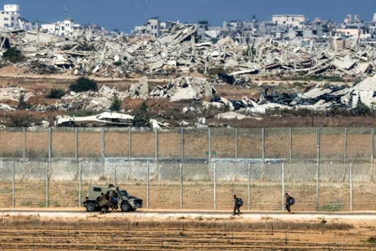 Des soldats de l'armée israélienne marchent vers un véhicule blindé à un poste situé dans le sud d'Israël le long de la barrière avec la bande de Gaza dévastée par la guerre, le 30 septembre 2025 ( AFP / Jack GUEZ )