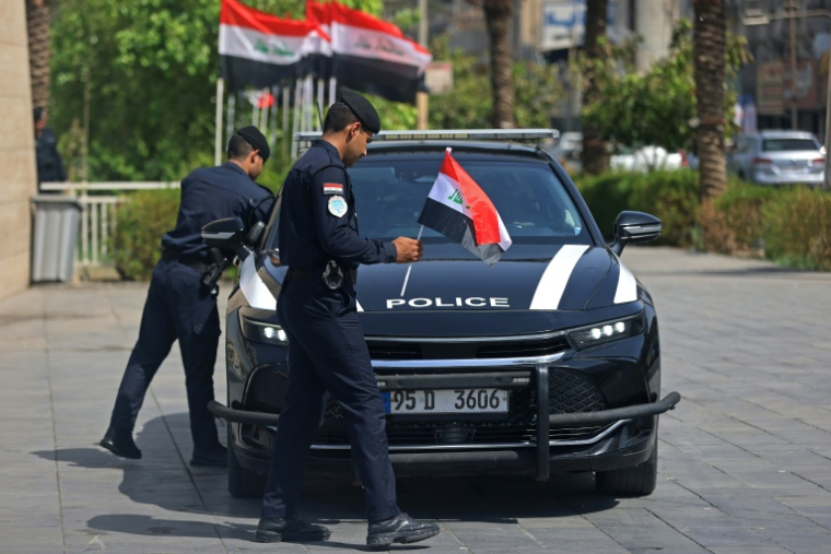Des policiers placent des drapeaux iraquiens sur leur véhicule à Bagdad le 29 septembre 2026 ( AFP / AHMAD AL-RUBAYE )
