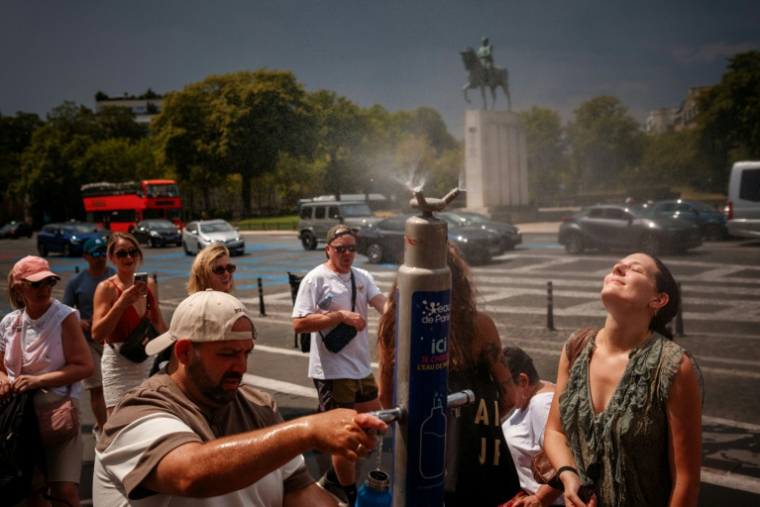 Des personnes se rafraîchissent autour d'une fontaine place du Trocadéro, à Paris, le 26 juin 2026 ( AFP / Dimitar DILKOFF )