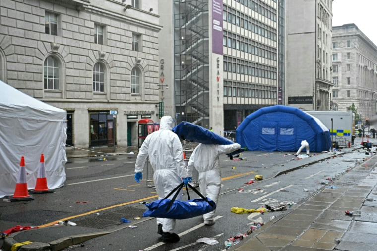 Des membres de la police scientifiqu esur les lieux où une voiture a foncé dans la foule lors de la parade de la victoire pour le trophée de la Premier League remporté club de football Liverpool FC, le 27 mai 2025 à Liverpool, dans le nord-ouest de l'Angleterre ( AFP / Paul ELLIS )