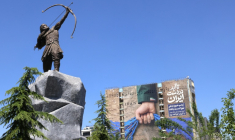 Une sculpture d'Arash l'Archer, figure légendaire de la mythologie persane, et une affiche géante représentant le détroit d'Ormuz avec l'inscription "À jamais dans la main de l'Iran", place Vanak à Téhéran, le 25 mai 2026 ( AFP / ATTA KENARE )