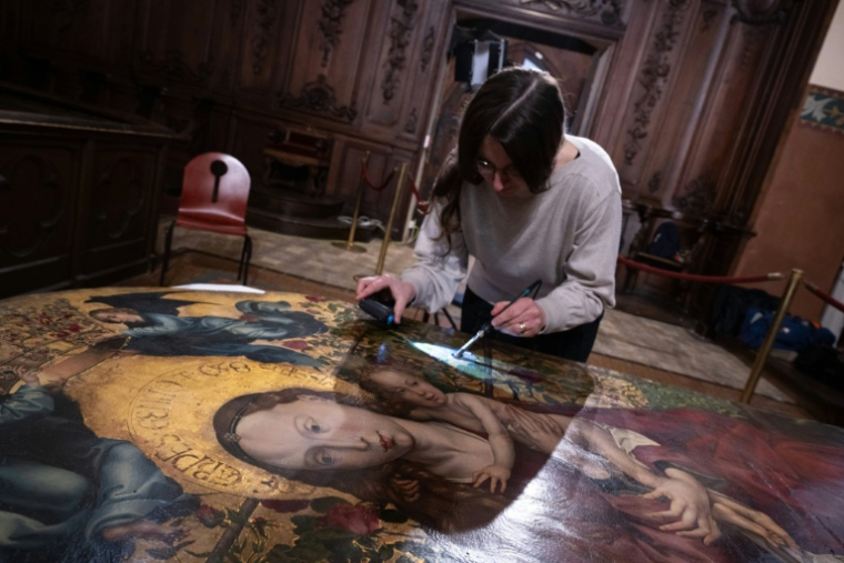 Une experte travaille à la restauration de "La Vierge au buisson de roses" peint par Martin Schongauer en 1473, le 5 mars 2026 à l'église des Dominicains de Colmar, dans le Haut-Rhin ( AFP / SEBASTIEN BOZON )