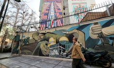 Un Iranien passe devant des fresques murales anti-américaines et anti-israéliennes, le 27 janvier 2026 à Téhéran  ( AFP / ATTA KENARE )