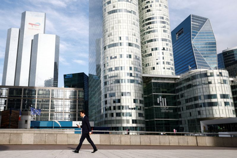 Un homme marche sur l'esplanade de La Défense
