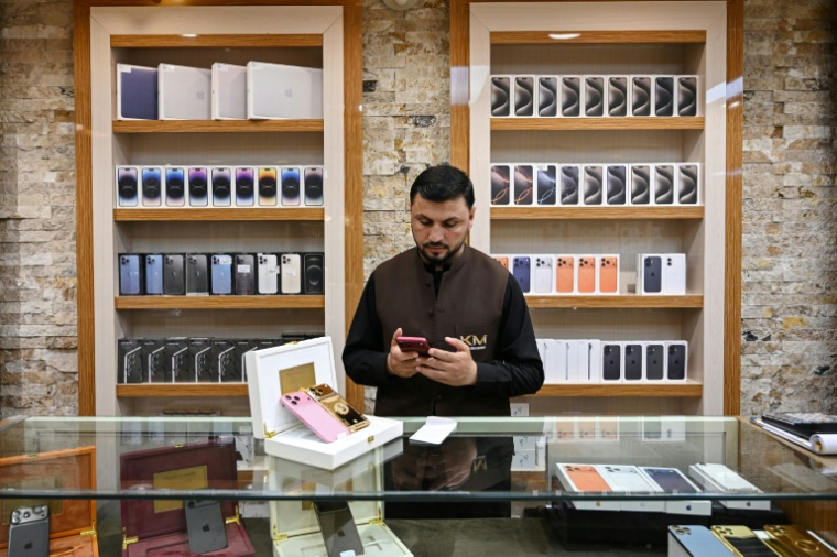 Un vendeur utilise un smartphone en attendant des clients dans un magasin à Kaboul, le 10 août 2026 en Afghanistan ( AFP / Wakil KOHSAR )
