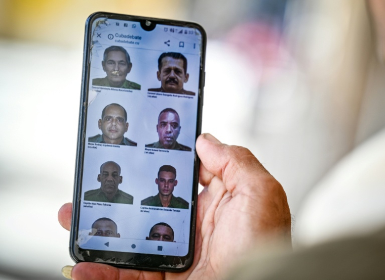 Un homme consulte sur son téléphone portable un site de la presse officielle cubaine où sont publiées les photos de certains des 32 officiers et soldats cubains tués lors de l'intervention militaire américaine au Venezuela, à La Havane, le 6 janvier 2026 ( AFP / Adalberto ROQUE )