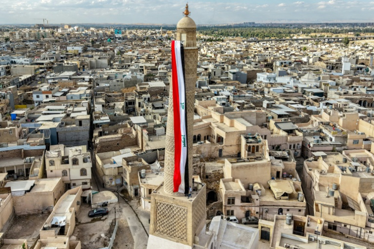 Un drapeau irakien géant est suspendu au minaret penché Hadba, datant du XIIᵉ siècle et reconstruit, dans la vieille ville de Mossoul, le 29 septembre 2026 ( AFP / Zaid AL-OBEIDI )