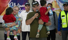 Le ministre vénézuélien de l'Intérieur Diosdado Cabello s'exprime en portant un enfant rapatrié aux côtés de la Première Dame Cilia Flores après l'arrivée d'un avion transportant des migrants vénézuéliens rapatriés des États-Unis à l'aéroport international Simon Bolivar à Maiquetia, au Venezuela, le 18 juillet 2025 ( AFP / Federico PARRA )
