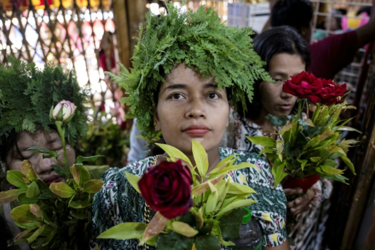 Des fidèles, coiffés de couronnes de feuillages et tenant des roses, participent à une procession traditionnelle lors du festival annuel des esprits de Taungbyone, dans la commune de Madayas située dans la région de Mandalay, le 26 août 2026 ( AFP / SAI AUNG MAIN )