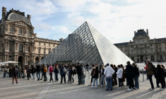 Des visiteurs font la queue devant la Pyramide du Louvre, conçue par l'architecte sino-américain Ieoh Ming Pei, et le musée du Louvre le jour de sa réouverture après un vol de bijoux, le 22 octobre 2025 à Paris ( AFP / Thibaud MORITZ )