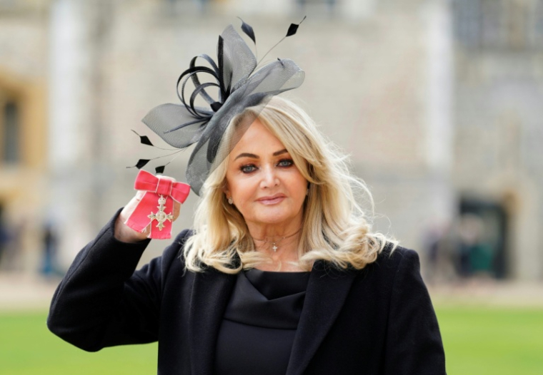 La chanteuse britannique Bonnie Tyler montre sa médaille après avoir été nommée membre de l'ordre de l'Empire britannique (MBE) lors d'une cérémonie au château de Windsor, le 1er février 2023 ( POOL / Andrew Matthews )