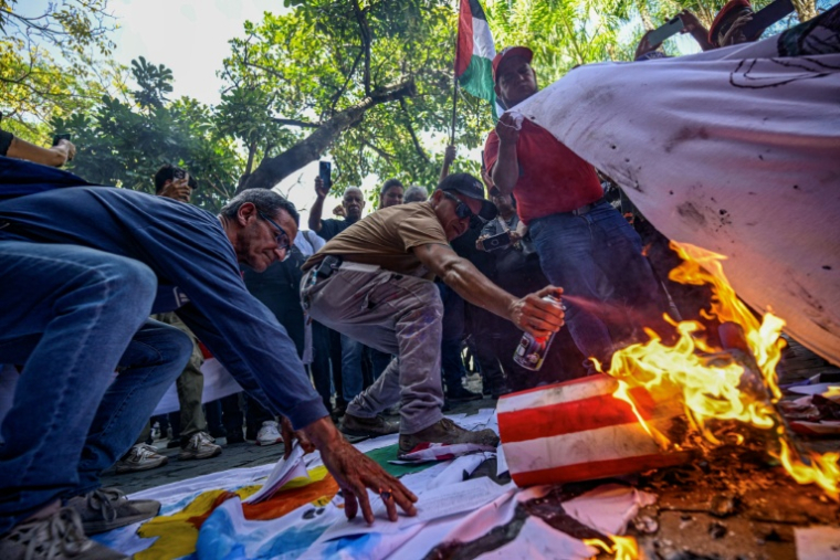 Des manifestants brûlent le drapeau des États-Unis et celui d’Israël lors d’une protestation à Caracas le 24 juillet 2026 ( AFP / Maxwell BRICENO )