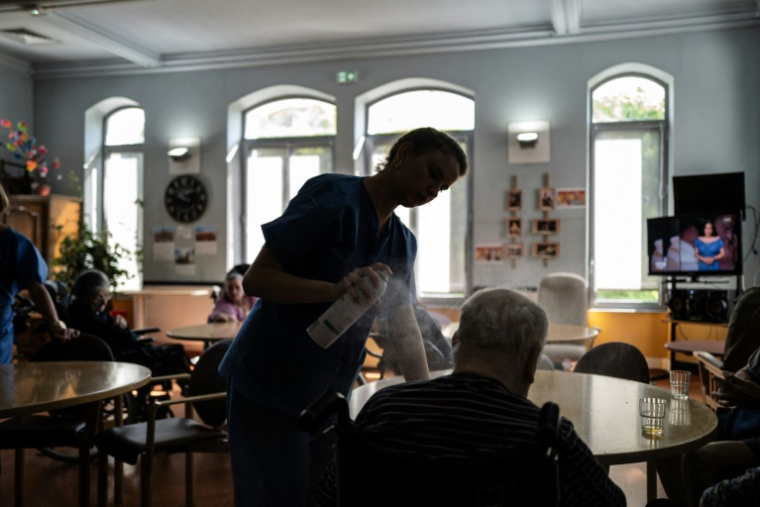 Une infirmière rafraîchit des personnes âgées dans une maison de retraite de Lyon le 1er juillet 2025 ( AFP / JEFF PACHOUD )