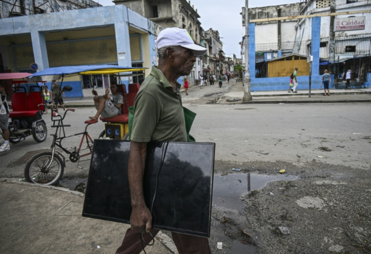 Un homme transporte un écran de télévision , dans une rue de La Havane, le 11 juillet 2026 ( AFP / YAMIL LAGE )