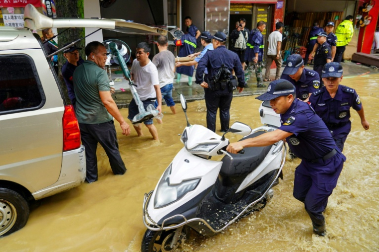 Une équipe aide à déplacer du matériel dans une rue inondée à Congjiang, dans la province de Guizhou, au sud-ouest de la Chine, le 24 juin 2025 ( AFP / STR )