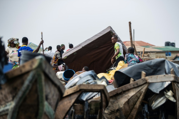 Des habitants transportent leurs affaires pendant la démolition du bidonville flottant de Makoko, le 9 janvier 2026 à Lagos, au Nigeria ( AFP / TOYIN ADEDOKUN )