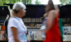 Des personnes passent devant des bouquinistes sur les quais de la Seine à Paris
