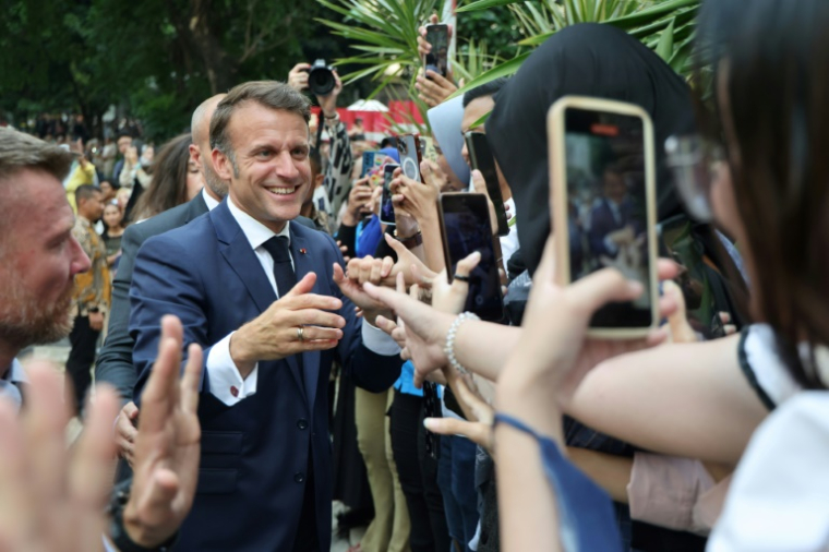 Le président français Emmanuel Macron salue des étudiants à son arrivée à l'Université nationale de Jakarta, le 28 mai 2025 ( AFP / Ludovic MARIN )