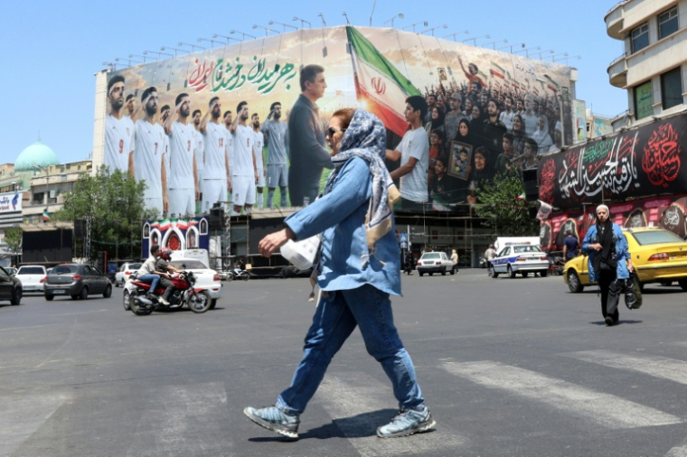 Une Iranienne passe devant un panneau montrant l'équipe de football de l'Iran, à Téhéran, le 18 mai 2026 ( AFP / - )