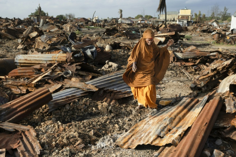 Une Somalienne récupère des tôles brûlées dans les ruines de son domicile, le 11 novembre près d'Awdheegle, une des localités récemment reprises aux rebelles islamistes shebab par l'armée nationale somalienne (SNA) ( AFP / Tony KARUMBA )