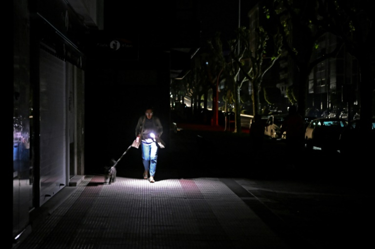 Une femme utilise son téléphone portable pour s'éclairer dans une rue de Vigo, le 28 avril 2025, au nord-ouest de l'Espagne, pendant la coupure d'électricité géante qui a affecté le pays ( AFP / MIGUEL RIOPA )