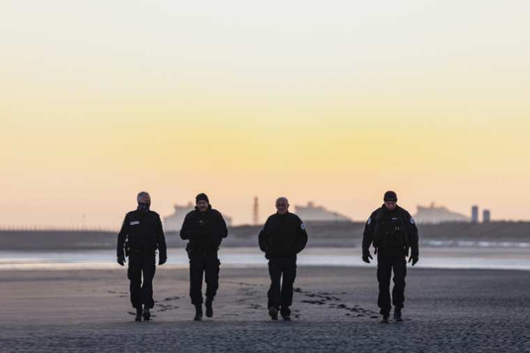 Des policiers français patrouillent sur la plage de Gravelines au lever du soleil afin d'empêcher les migrants de traverser la Manche, à Gravelines, dans le nord de la France, le 14 avril 2026 ( AFP / Sameer Al-DOUMY )