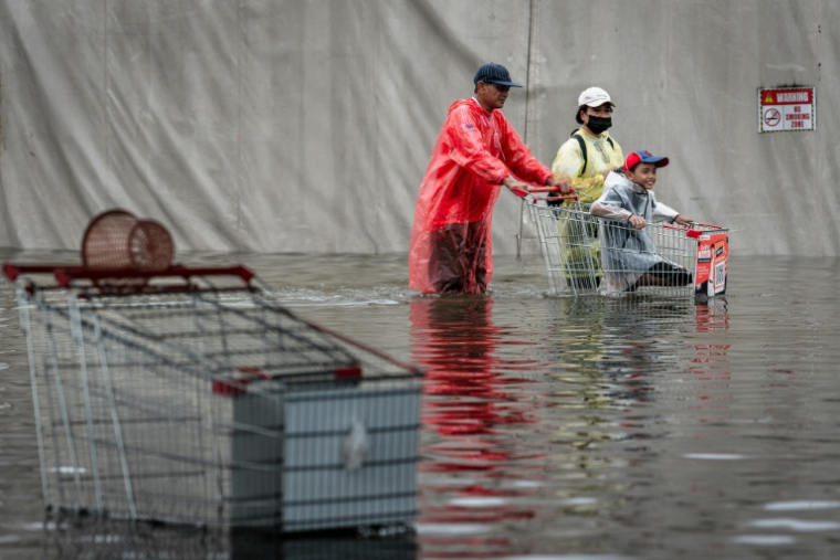 Des habitants dans une rue de Bangkok, où l'état de catastrophe naturelle a été déclaré après des pluies diluviennes qui ont inondé habitations, commerces et axes de circulation, le 27 septembre 2026 ( AFP / Chanakarn LAOSARAKHAM )