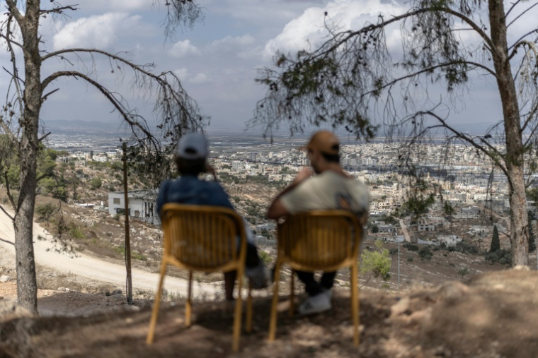 Des colons israéliens sont assis sur une colline dans la colonie de Kadim surplombant la ville palestinienne de Jénine, en Cisjordanie occupée, le 30 septembre 2026 ( AFP / Ilia YEFIMOVICH )