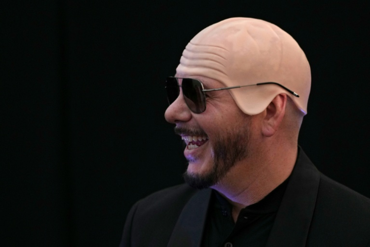 Le rappeur américain Pitbull porte un faux crâne chauve en latex après avoir établi un record Guinness du plus grand rassemblement de personnes portant de faux crânes chauves, le 10 juillet 2026 à Londres ( AFP / CARLOS JASSO )