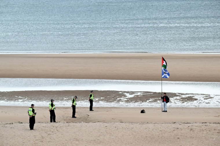 Un manifestant solitaire brandit des drapeaux palestinien et écossais à Balmedie Beach, en Ecosse, pendant un séjour dans la région du président américain Donald Trump le 28 juillet 2025 ( AFP / LESLEY MARTIN )