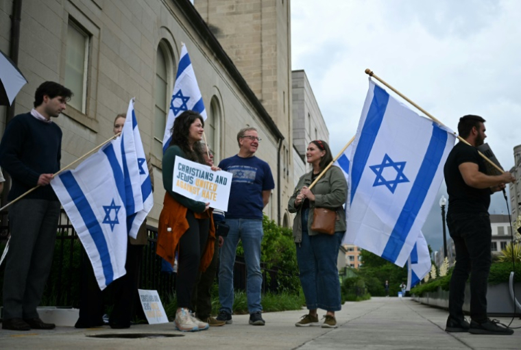 Des personnes brandissent des pancartes et des drapeaux israéliens en signe de soutien devant le Musée juif de Washington, aux Etats-Unis, le 22 mai 2025 ( AFP / Drew ANGERER )